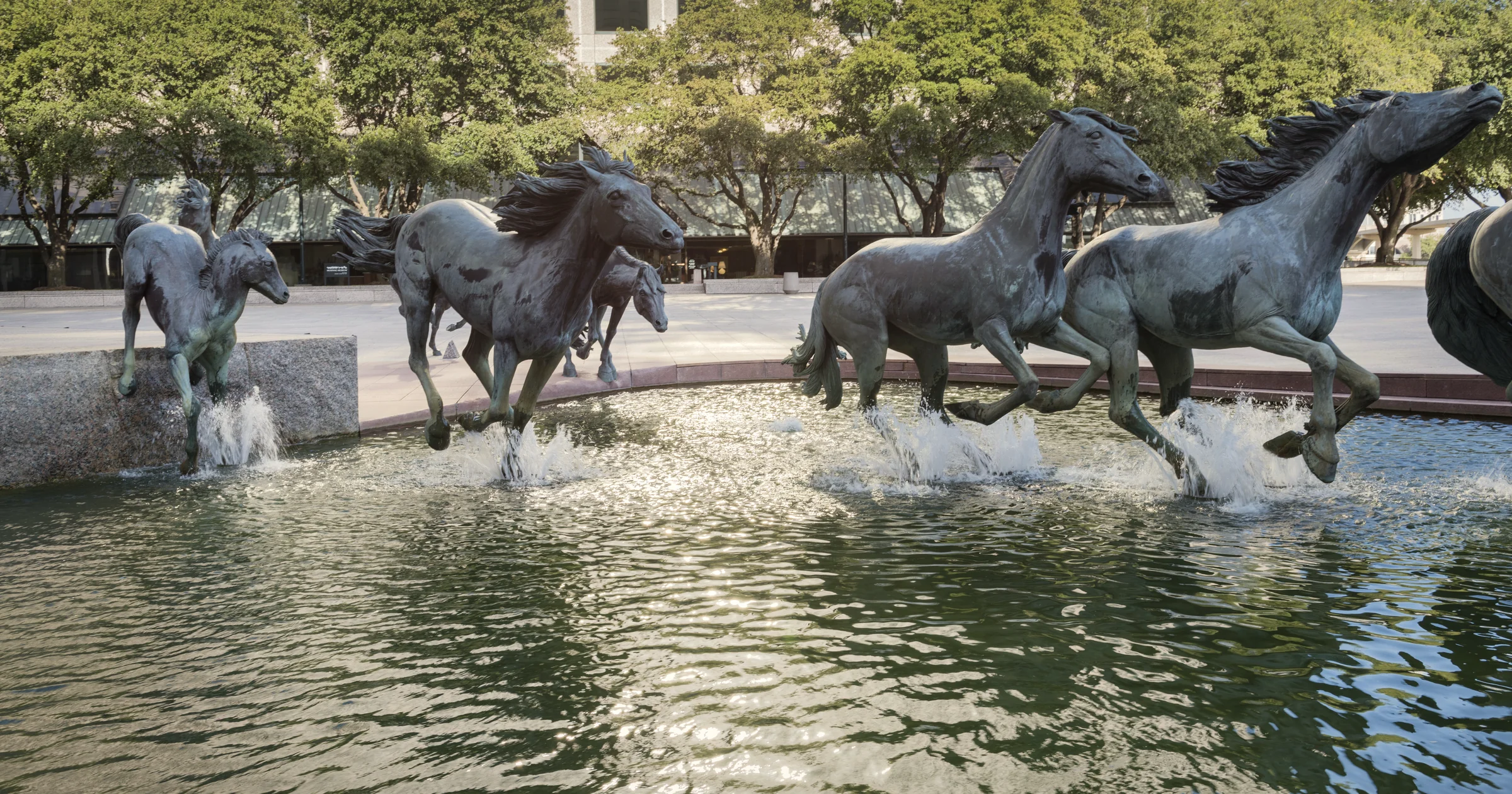Bronze Mustangs of Las Colinas sculpture galloping through the fountain at Williams Square, Irving, Texas