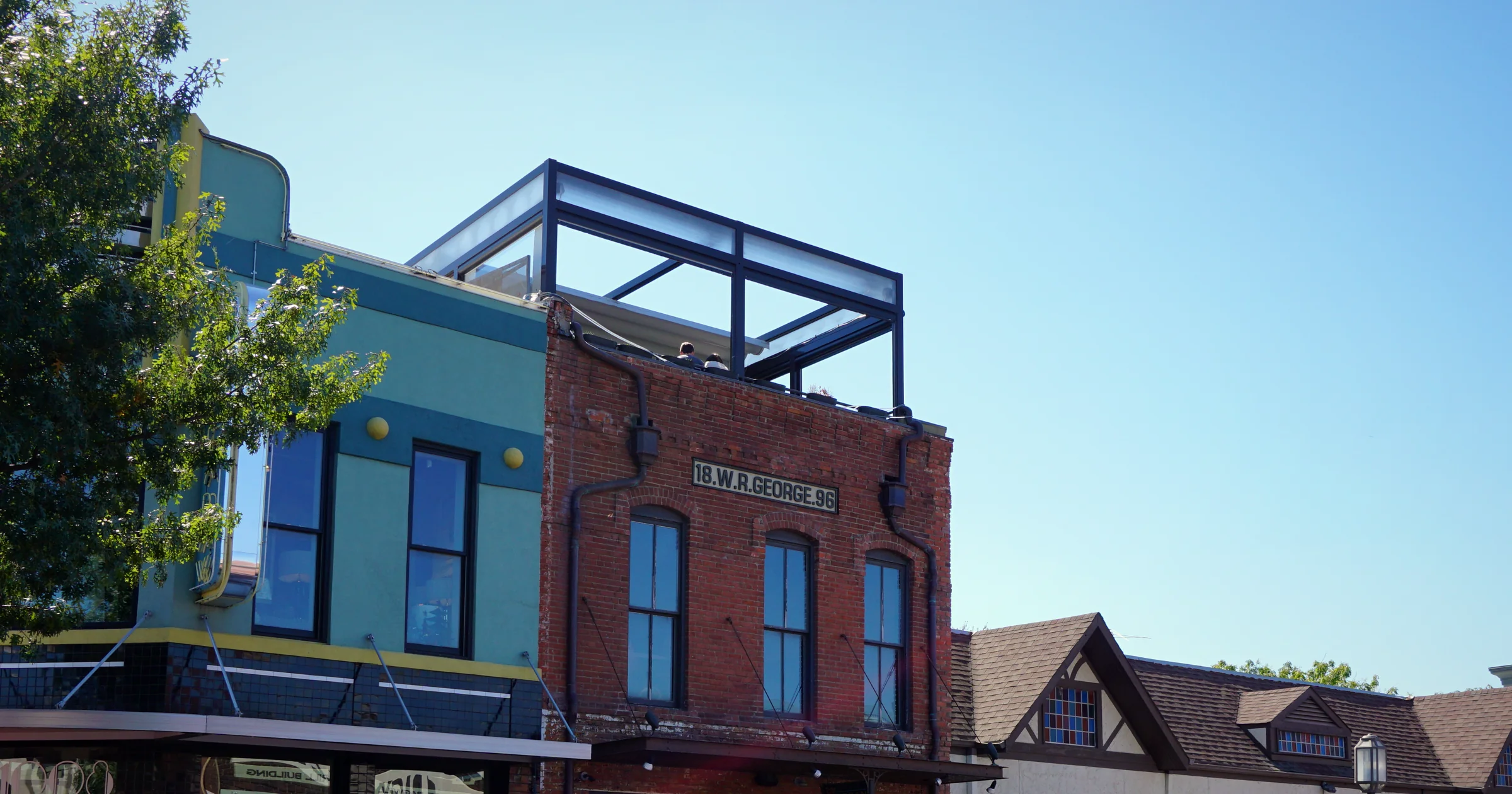 Historic brick and teal storefronts on 15th Street in downtown Plano, Texas, under a clear blue sky