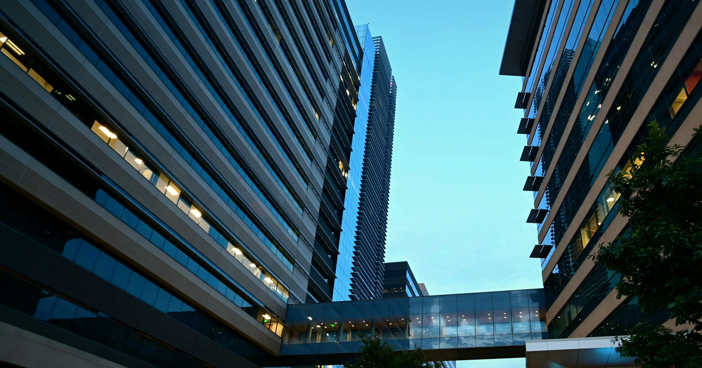 Glass office towers and a skybridge on State Street at CityLine in Richardson, Texas, against a blue sky