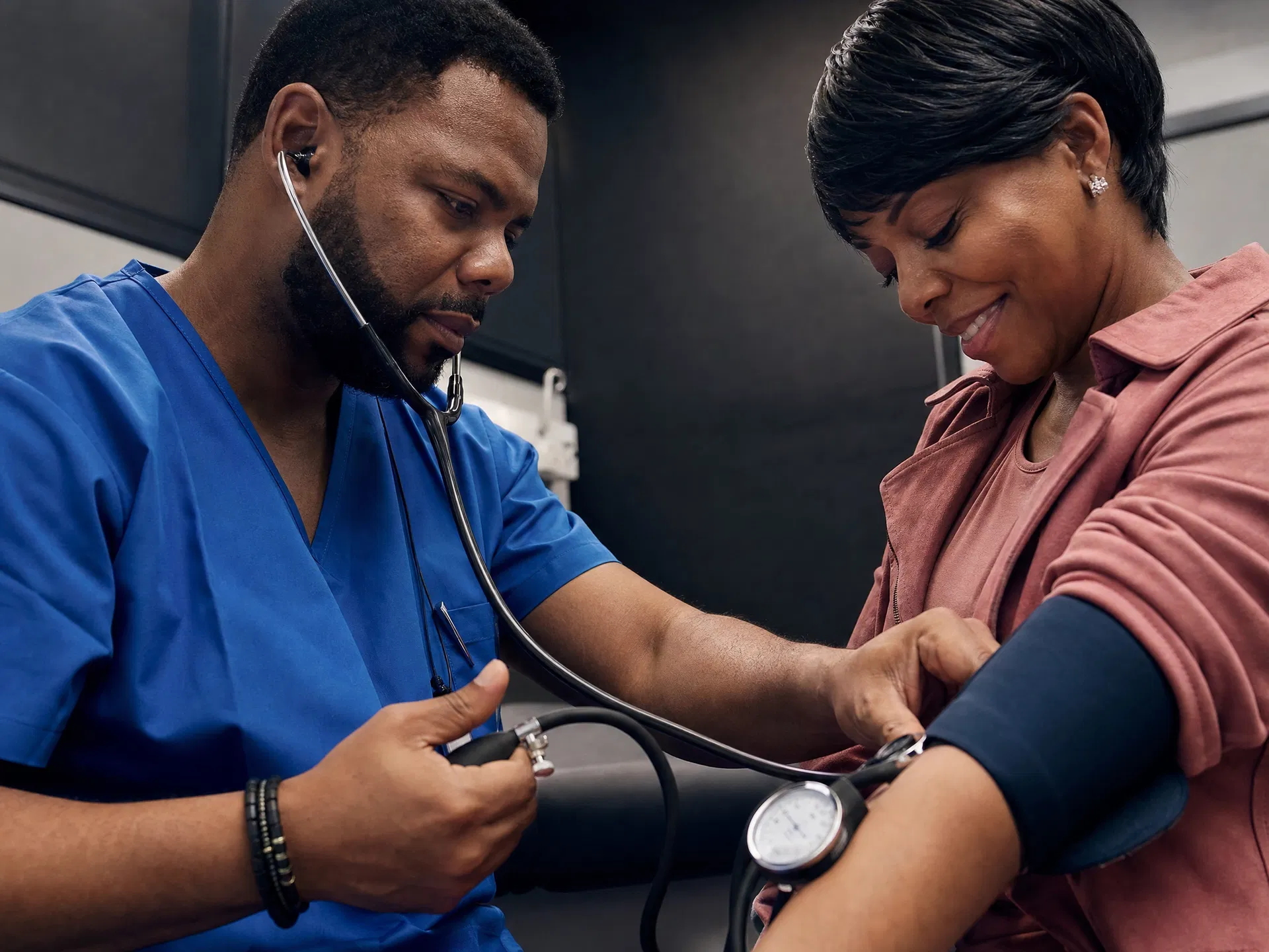 Doctor taking blood pressure of patient in exam room